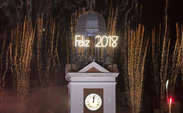 El reloj de la Puerta del Sol da la bienvenida al nuevo año en una celebración que concentró a miles de personas en la popular plaza madrileña . /Rodrigo Jiménez (Efe)